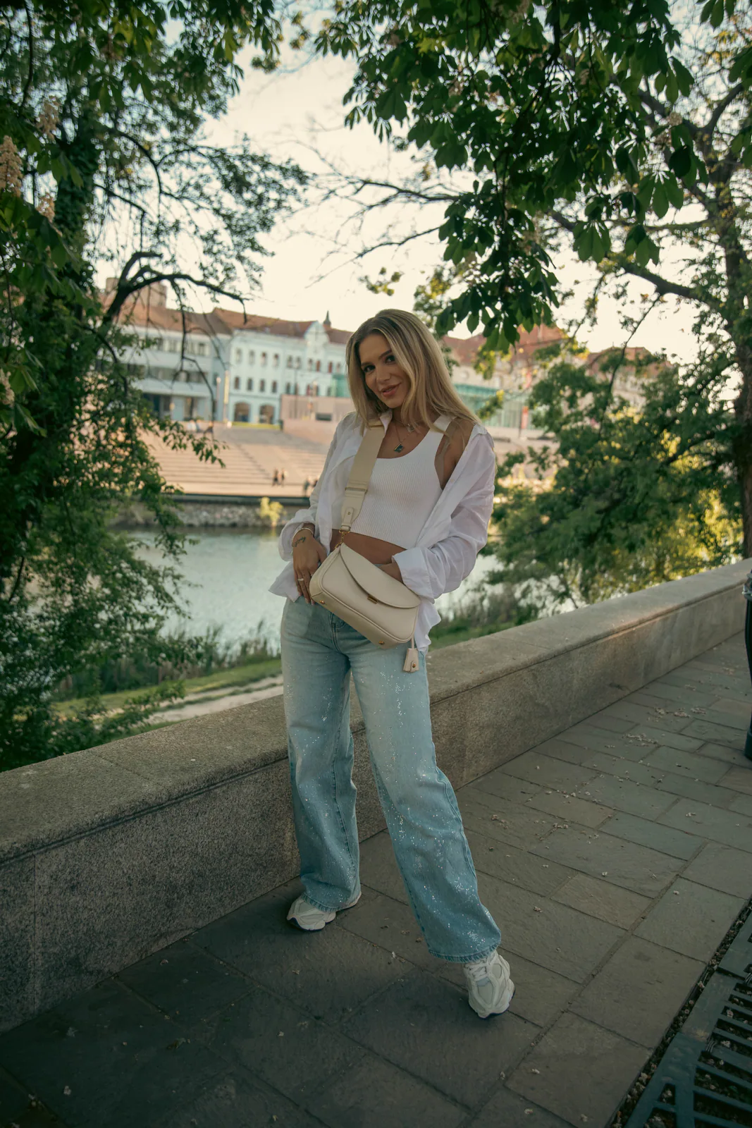 Woman in a light outfit standing on a riverside path