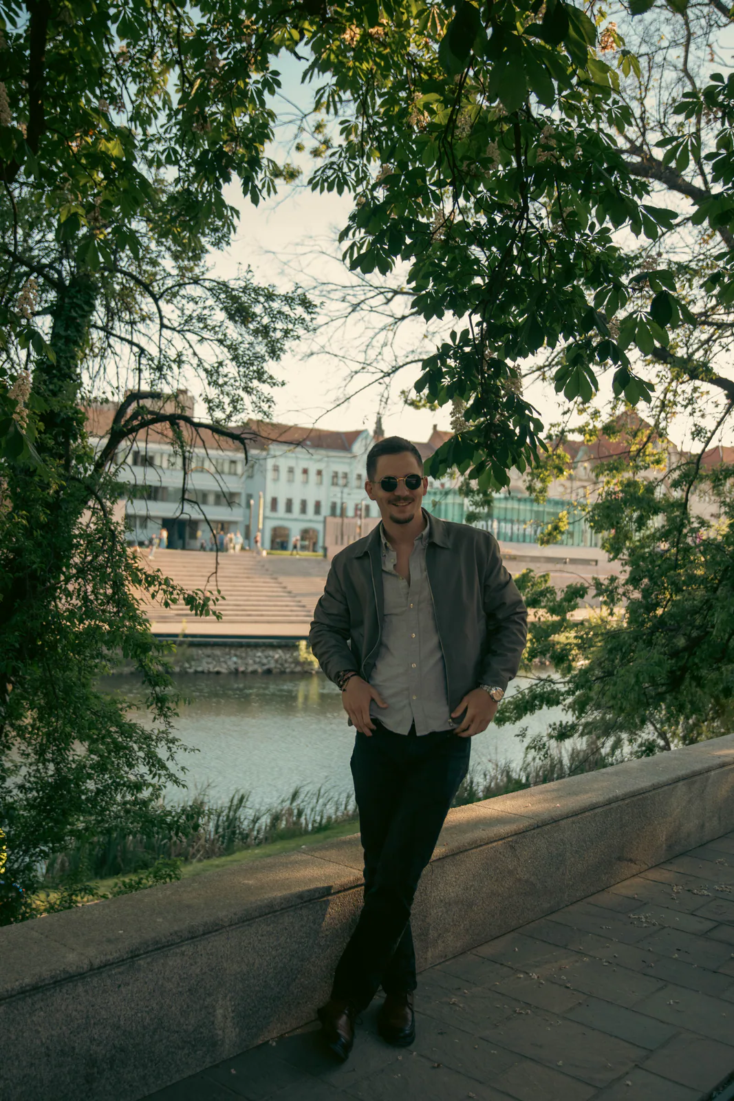 Man in a jacket walking beside an urban waterfront