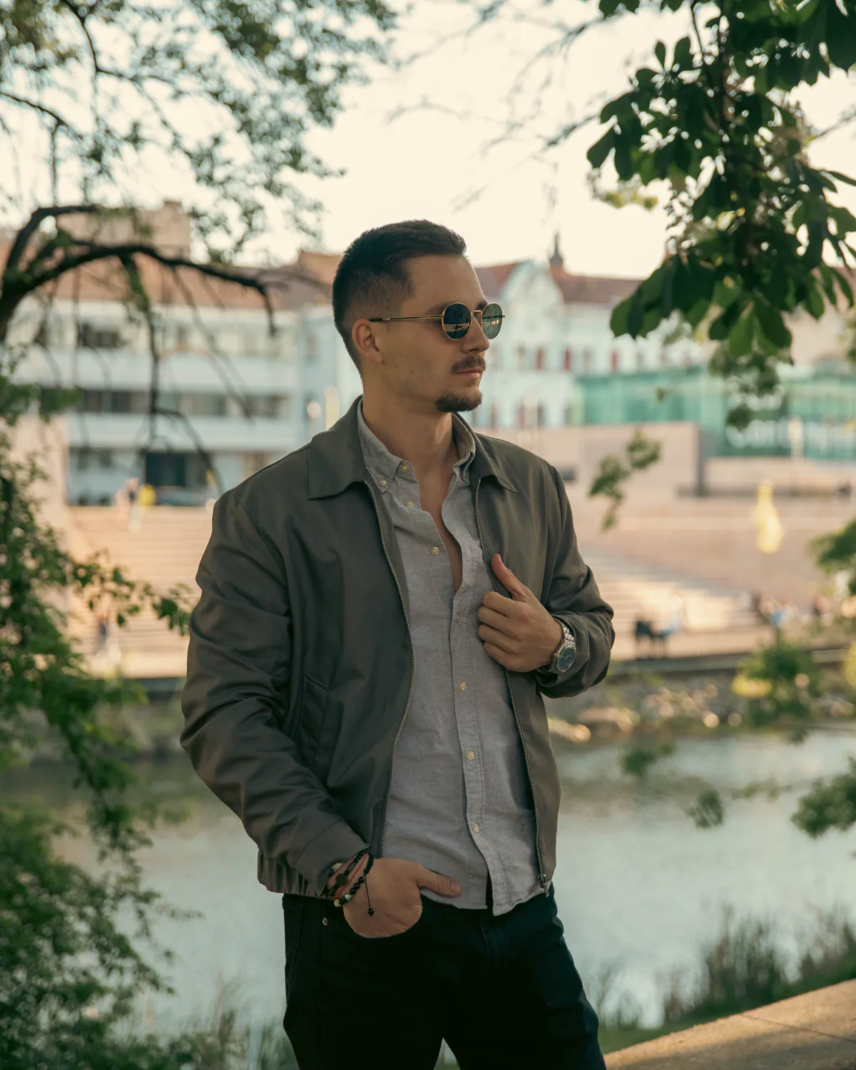 Man posing beneath trees beside the water