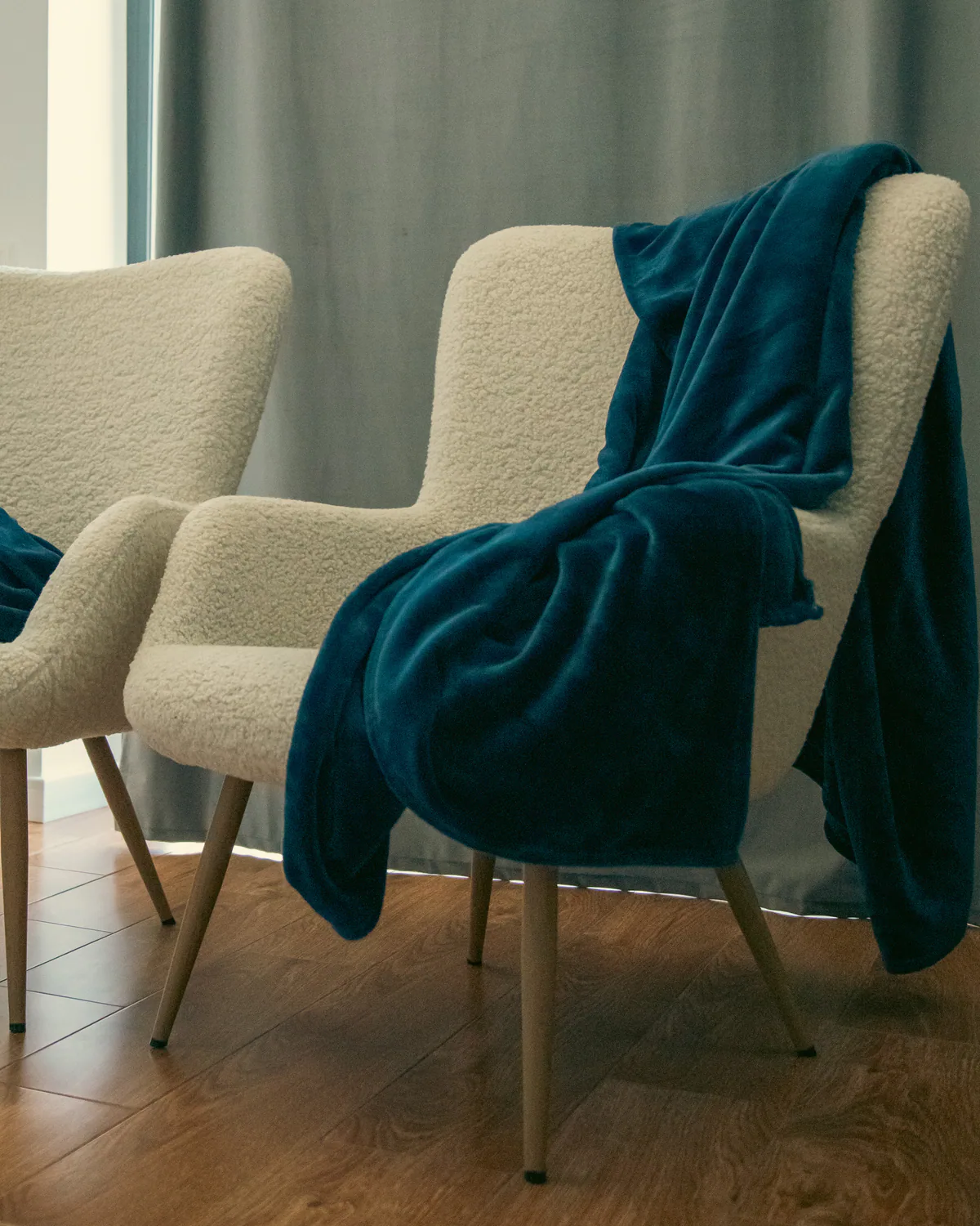Cream bouclé chairs with a deep blue blanket draped over them