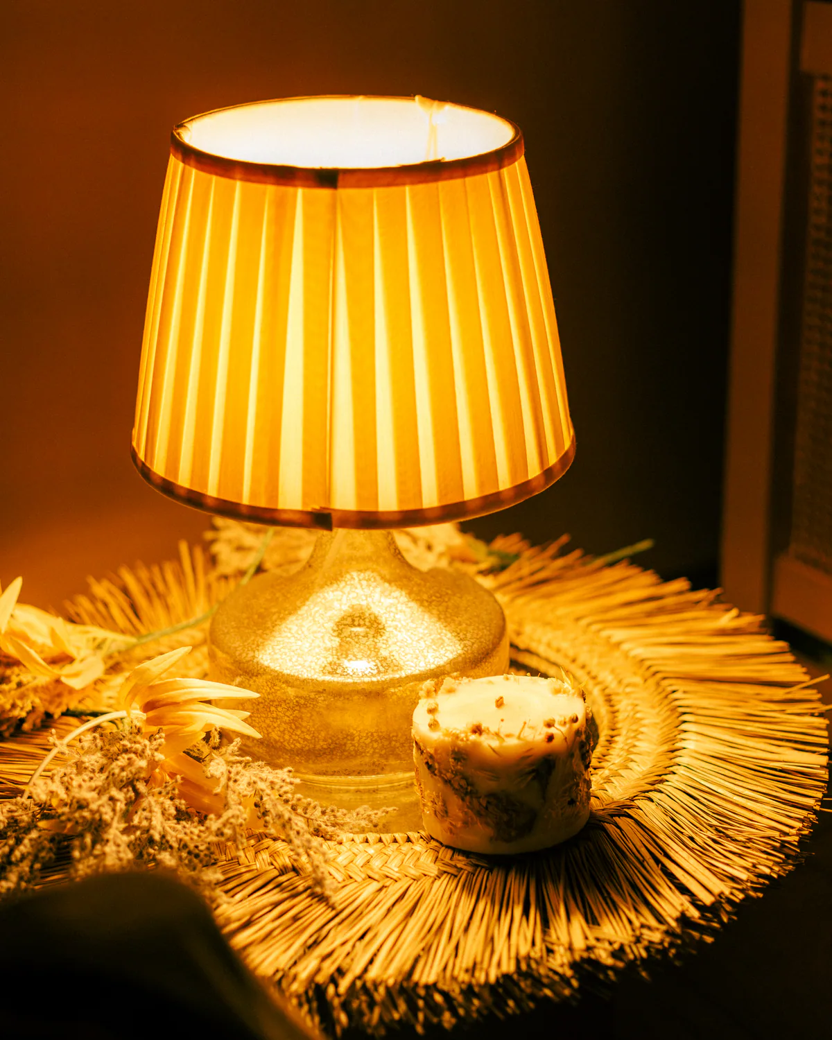 Candle and pleated lamp creating warm ambient light