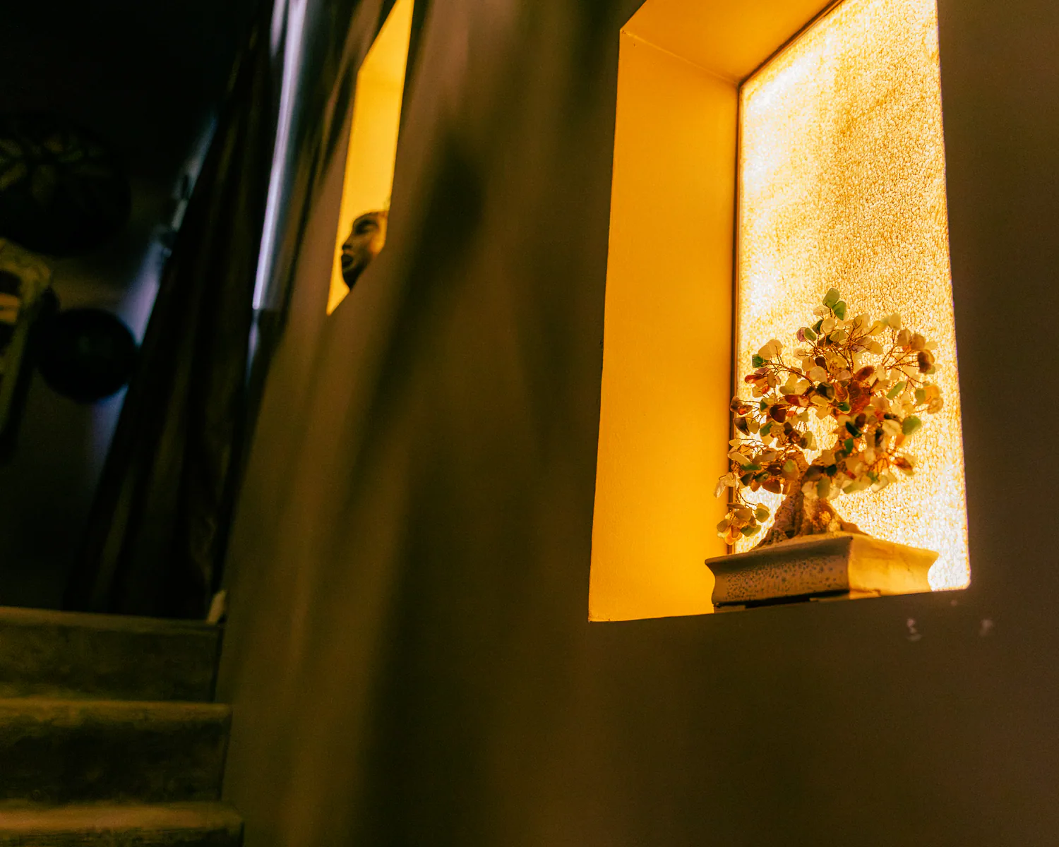 Decorative gemstone tree displayed in a glowing wall niche