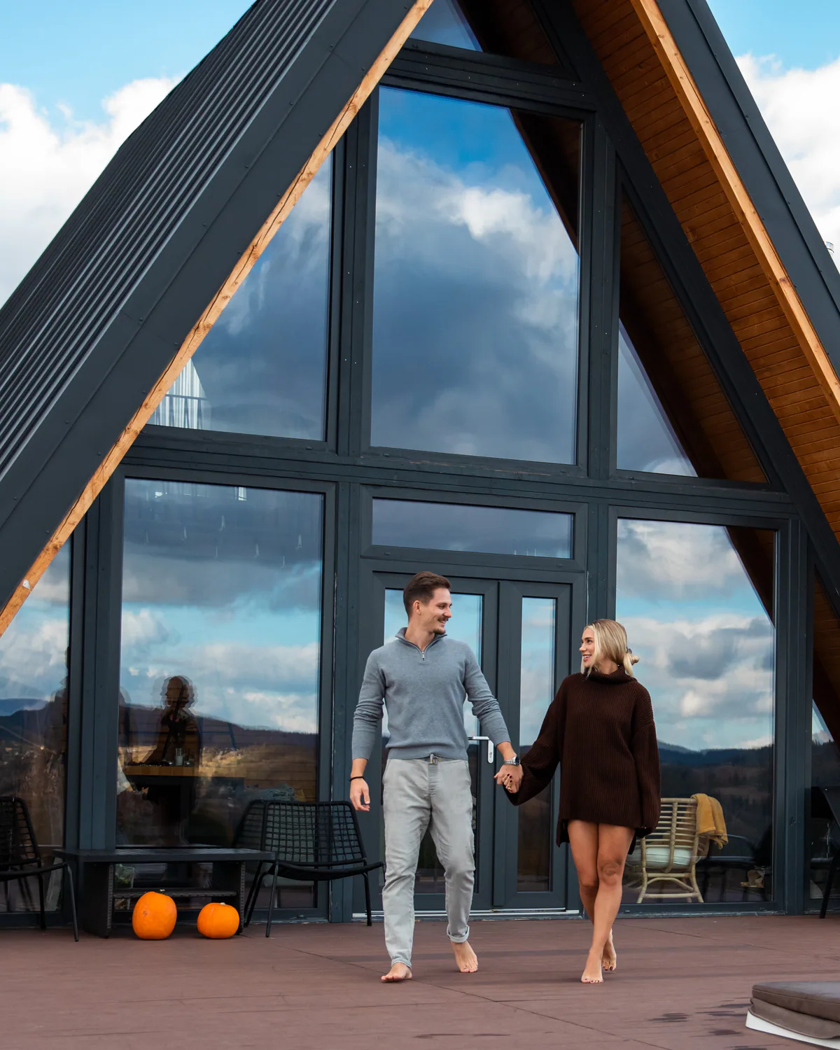 Couple standing in front of the glass-fronted A-frame cabin