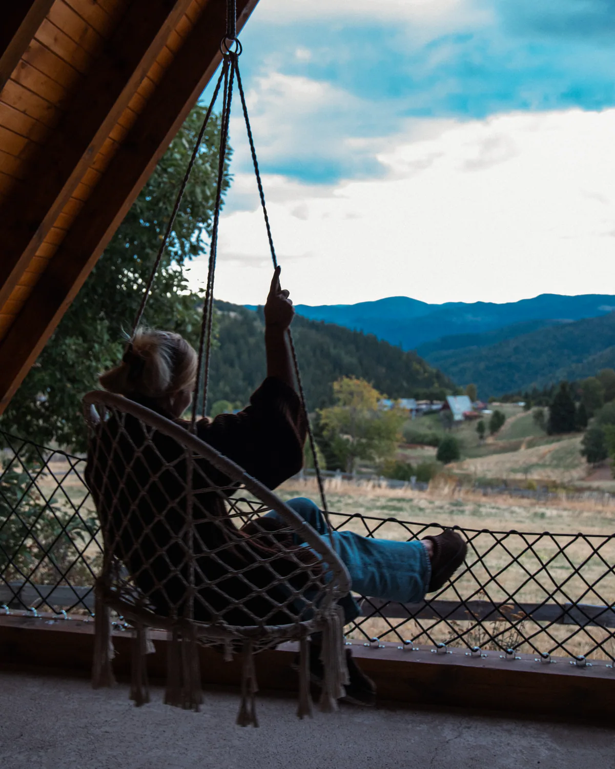 Woman relaxing in a hanging chair overlooking the mountains
