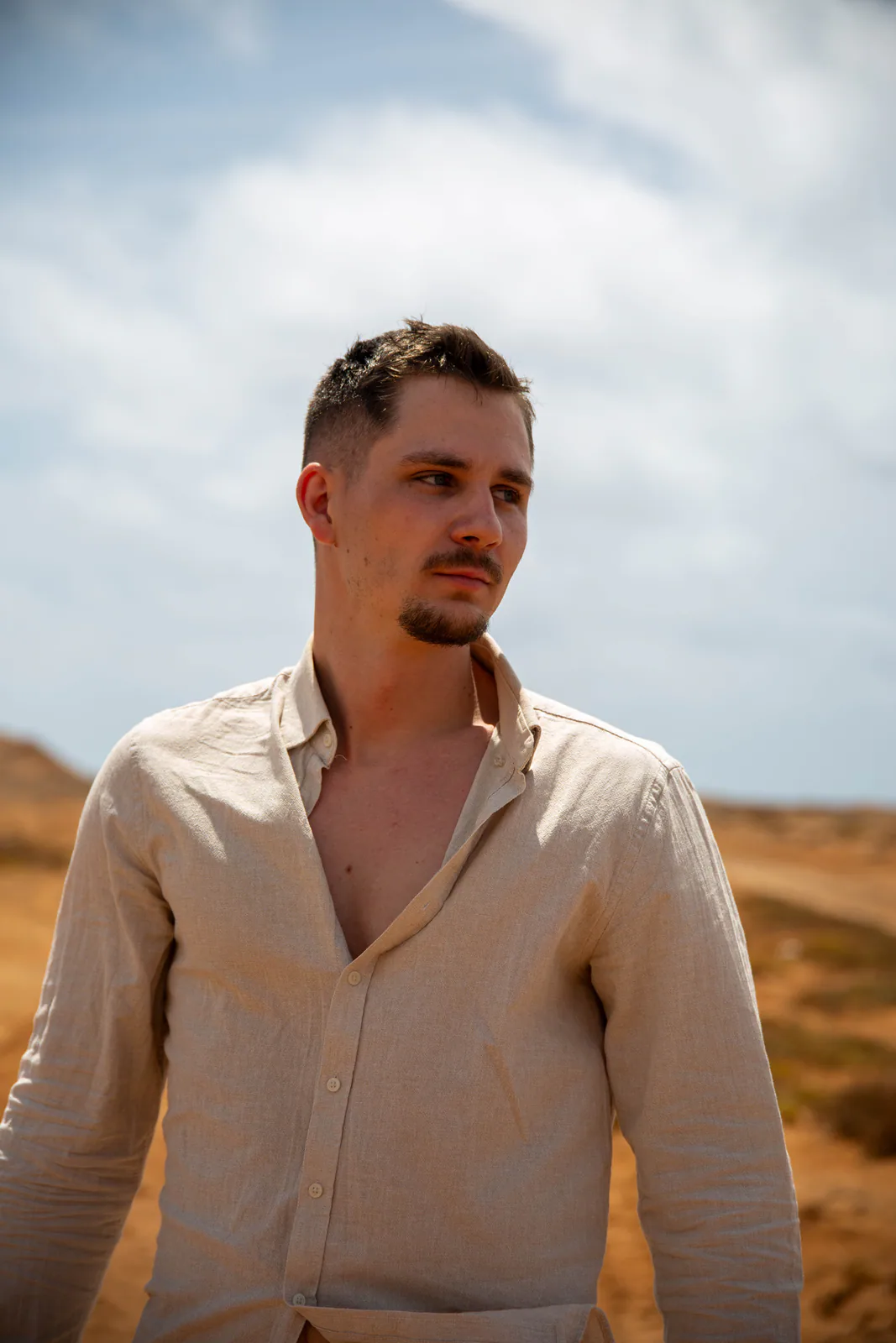 Man in a light shirt standing in a sandy landscape