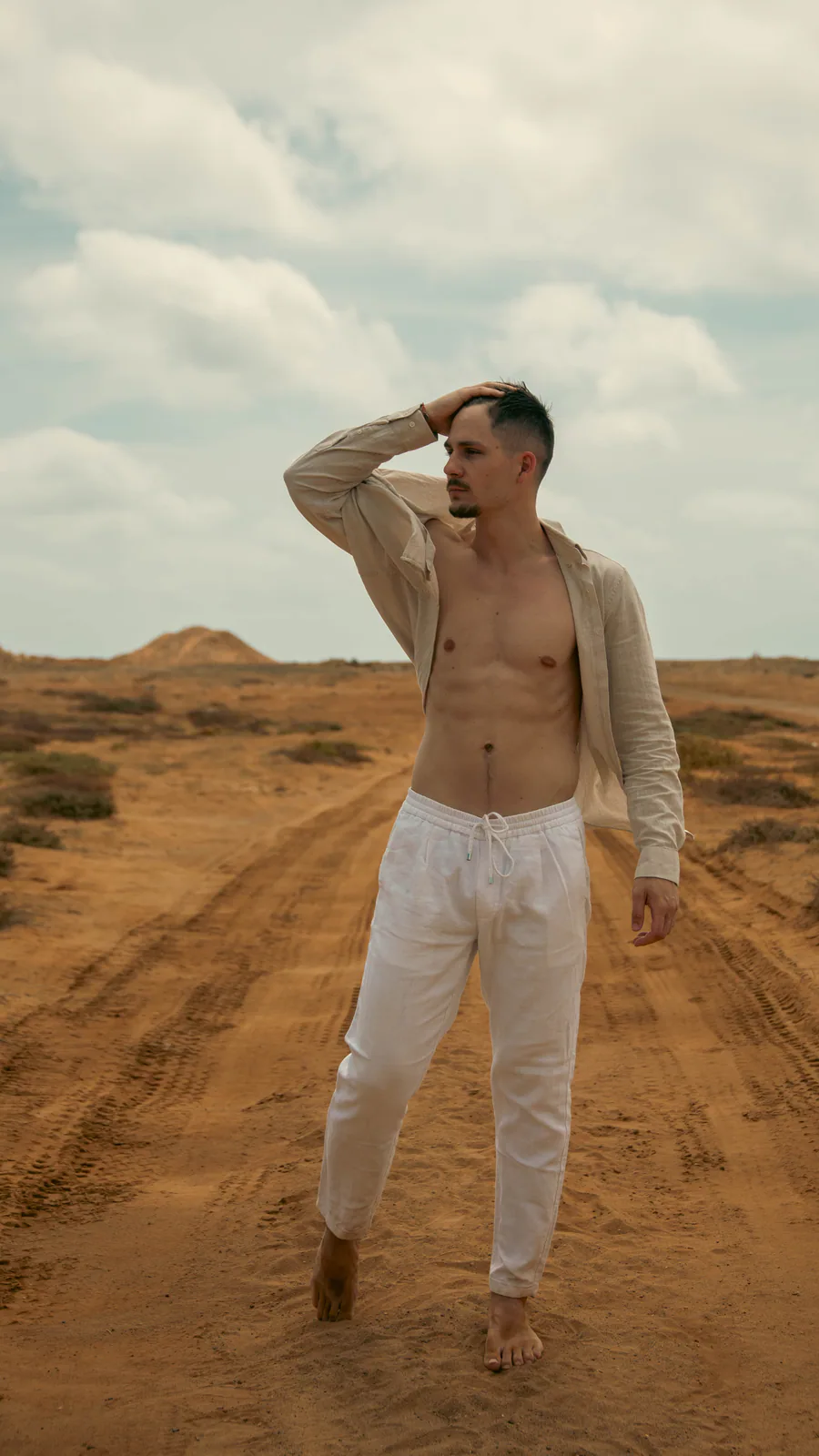 Man in light clothing standing in an open sandy landscape