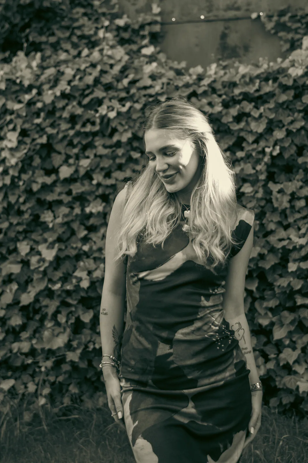 Woman standing beside an ivy-covered wall