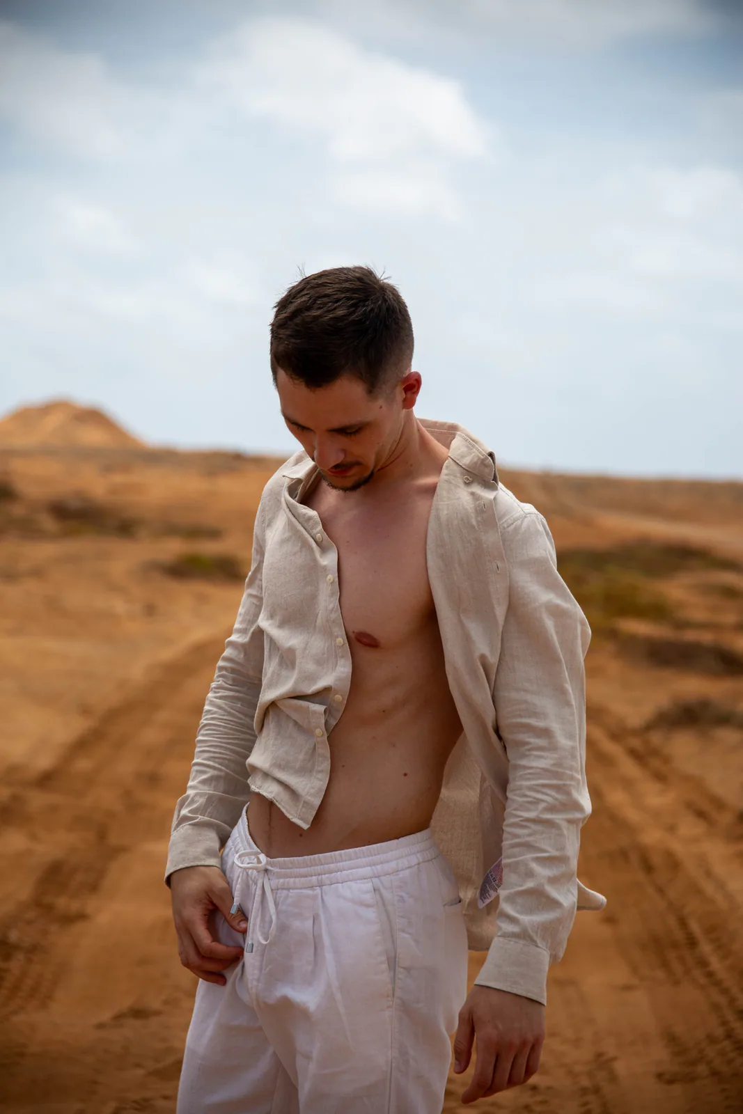 Man looking down while posing in a sandy landscape