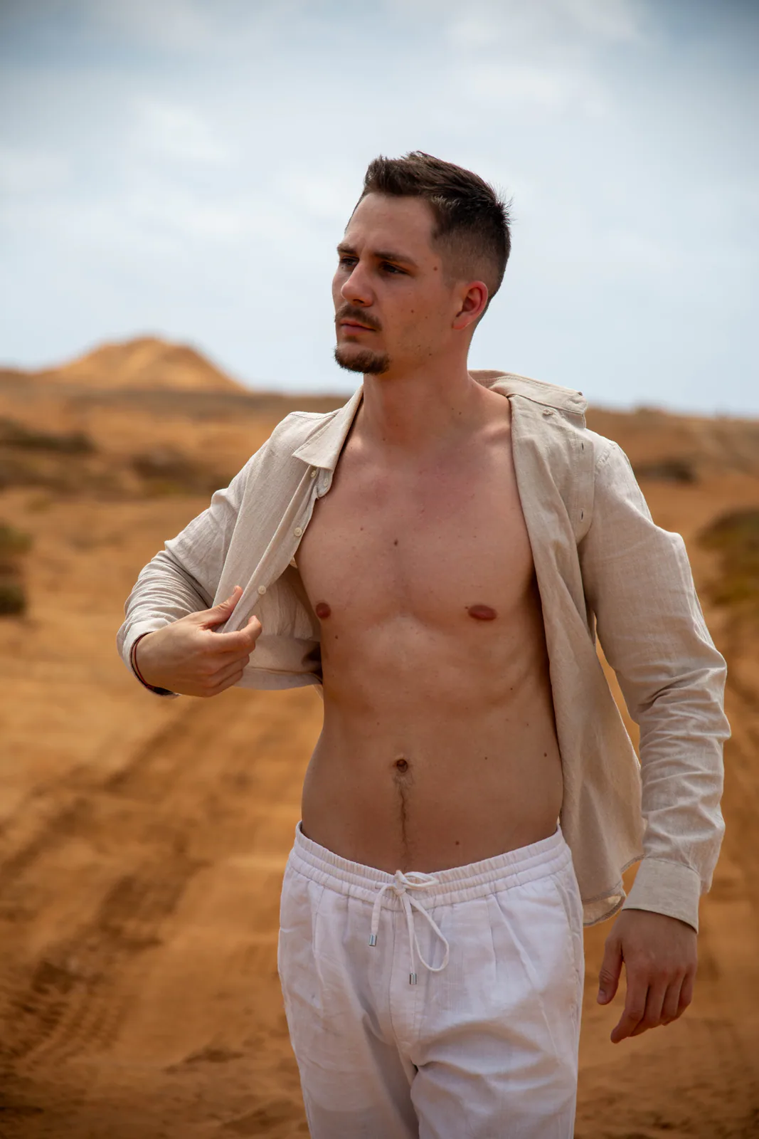 Man styling a light shirt in a sandy landscape