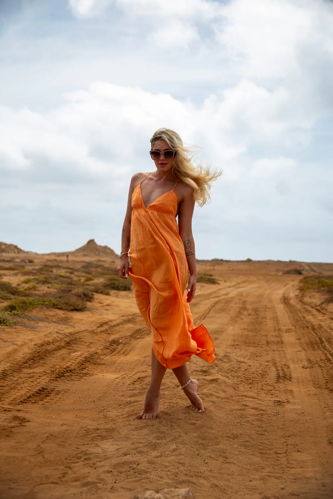Woman in an orange dress walking through an open landscape