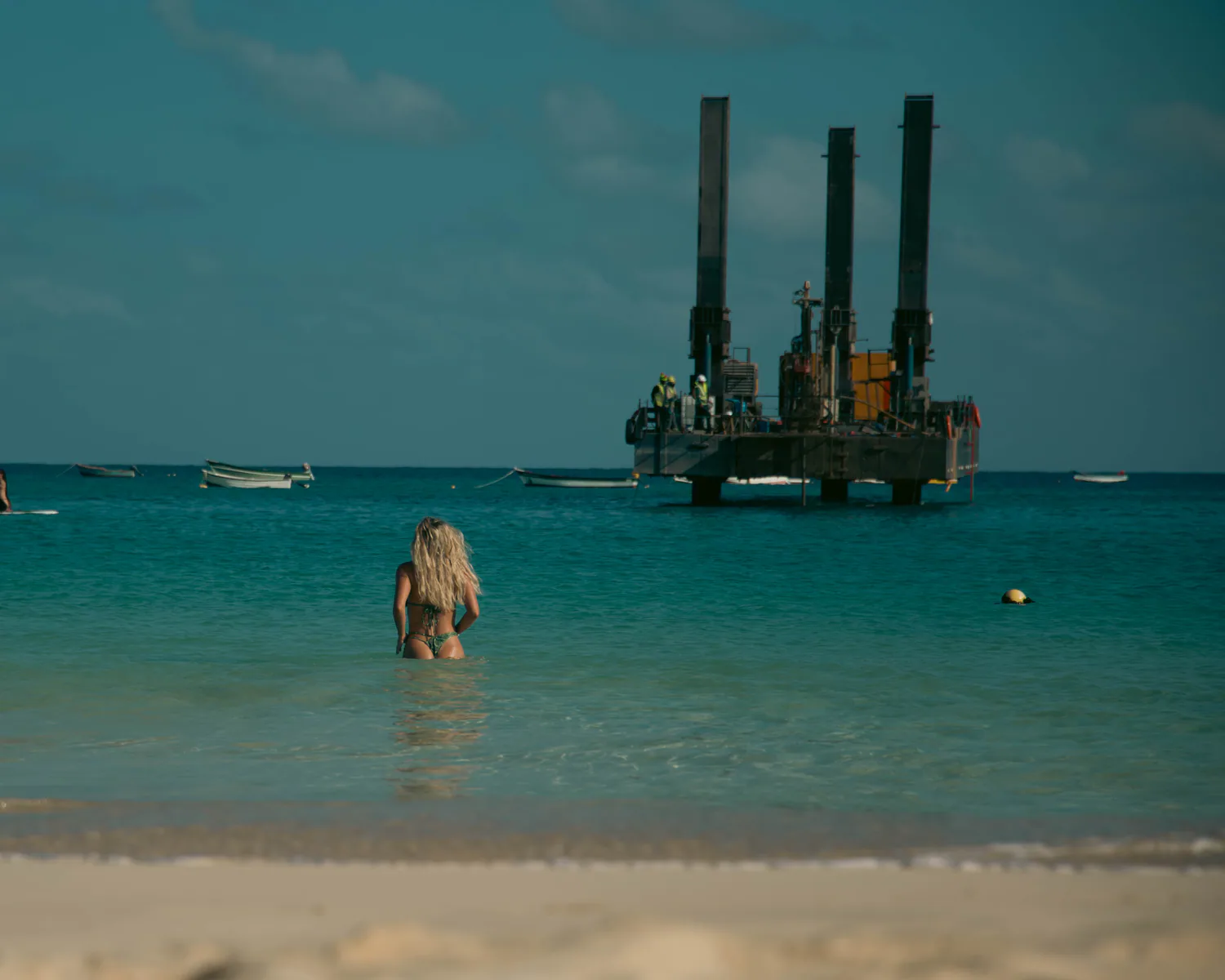 Distant figure standing in clear coastal water